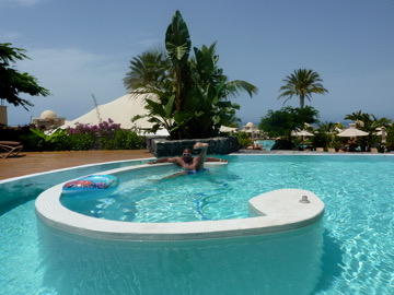 Chris relaxing in a tropical pool surrounded by palms
